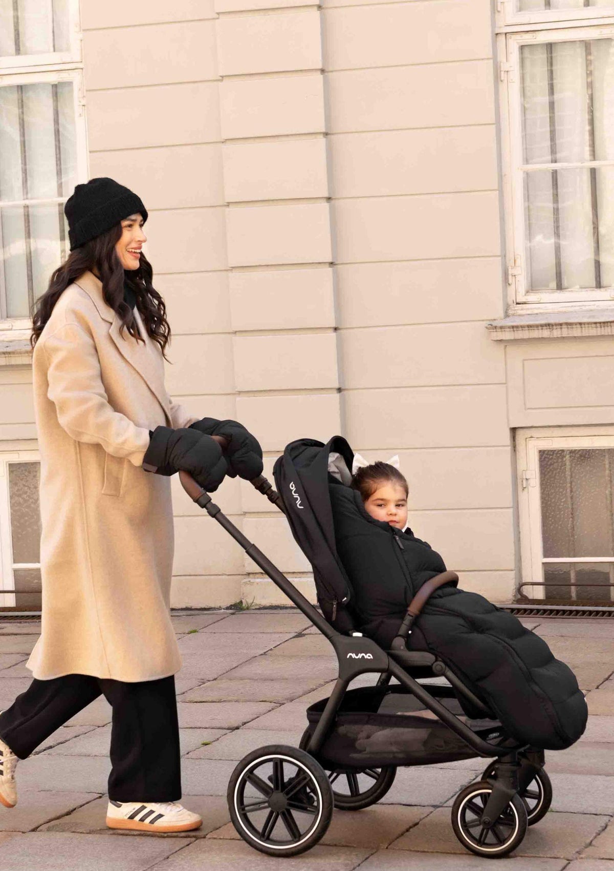 Frau schiebt Nuna Sportwagen TRIV lx Caviar mit Winter-Set (Fußsack und Handschuhe)