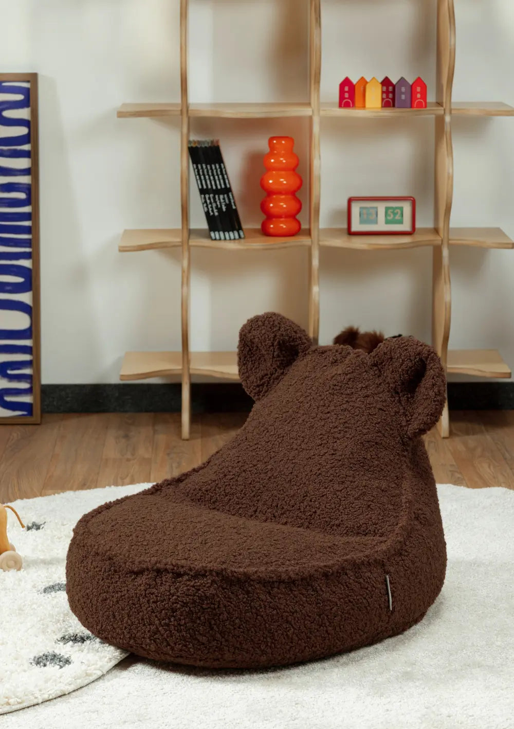 Der dunkelbraune Wigiwama Bären Sitzsack Teddy Warm Hazel aus flauschigem Teddy-Stoff steht freistehend auf einem hellen Teppich in einem modernen Zimmer.