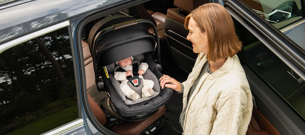 Nuna PIPA next Babyschale mit Basisstation BASE curv, mit 360° Drehung - im Bild: Baby im Kindersitz im Auto
