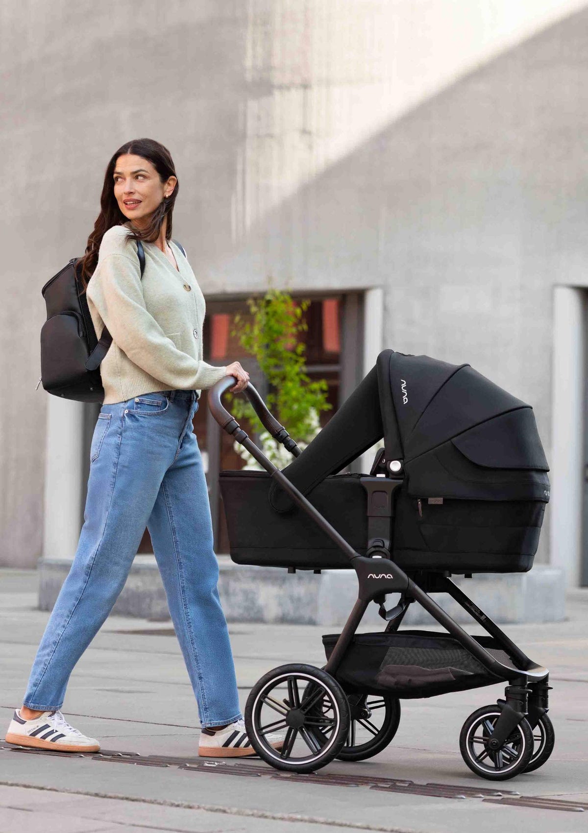 Frau schiebt Nuna Kinderwagen TRIV lx Caviarmit Babywanne