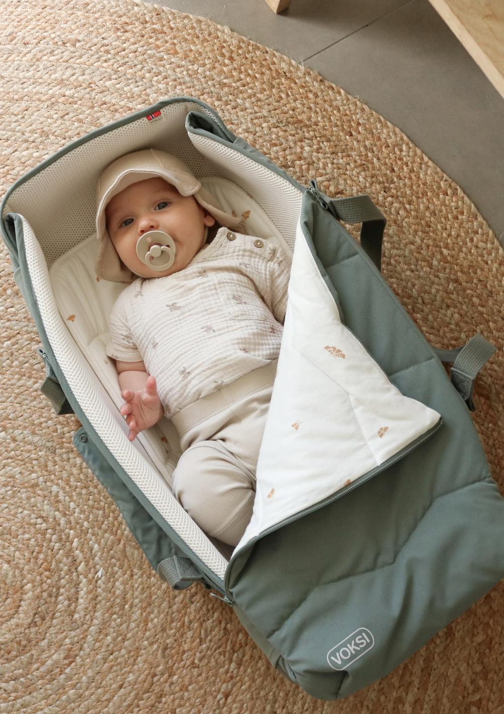 Baby liegt in Voksi Babytragetasche 'Carry Me' Meadow Green Leaf