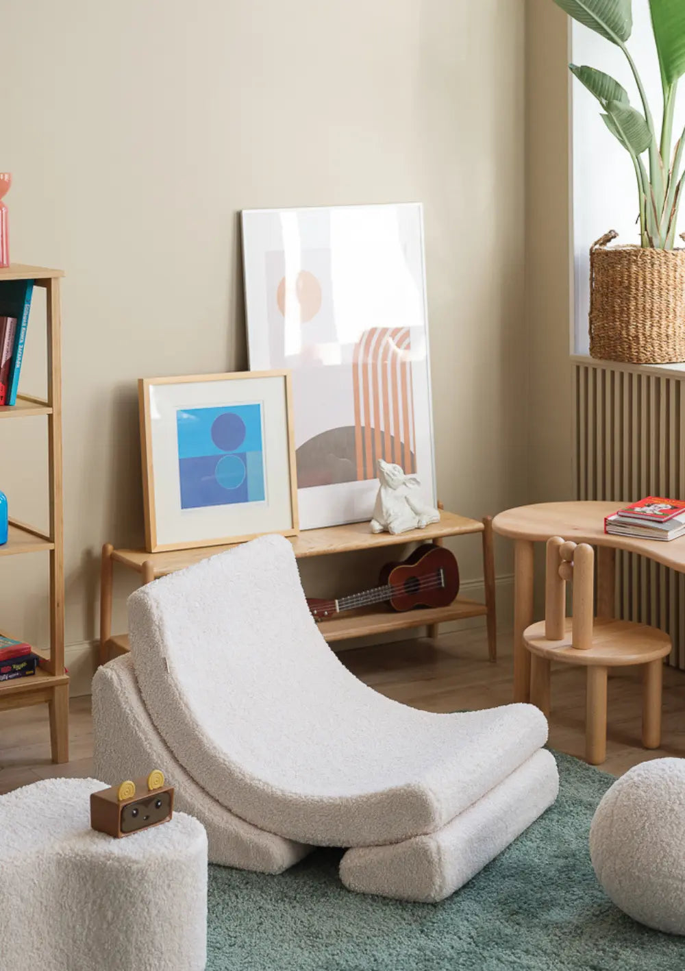 Der cremeweiße Wigiwama Kindersessel Moon Chair Teddy Cream White aus flauschigem Teddy-Plüsch steht freistehend auf einem grünen Teppich in einem modern eingerichteten Kinderzimmer.
