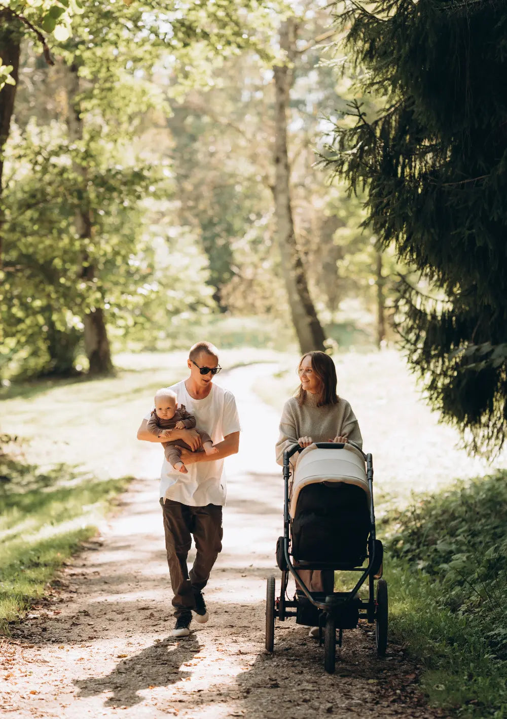 Elternpaar mit Baby beim Waldsapziergang mit dem tfk Kinderwagen-Set 'pro' Sand
